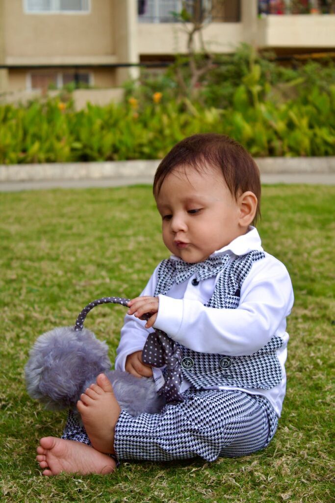 toddler playing with earmuffs on a green lawn