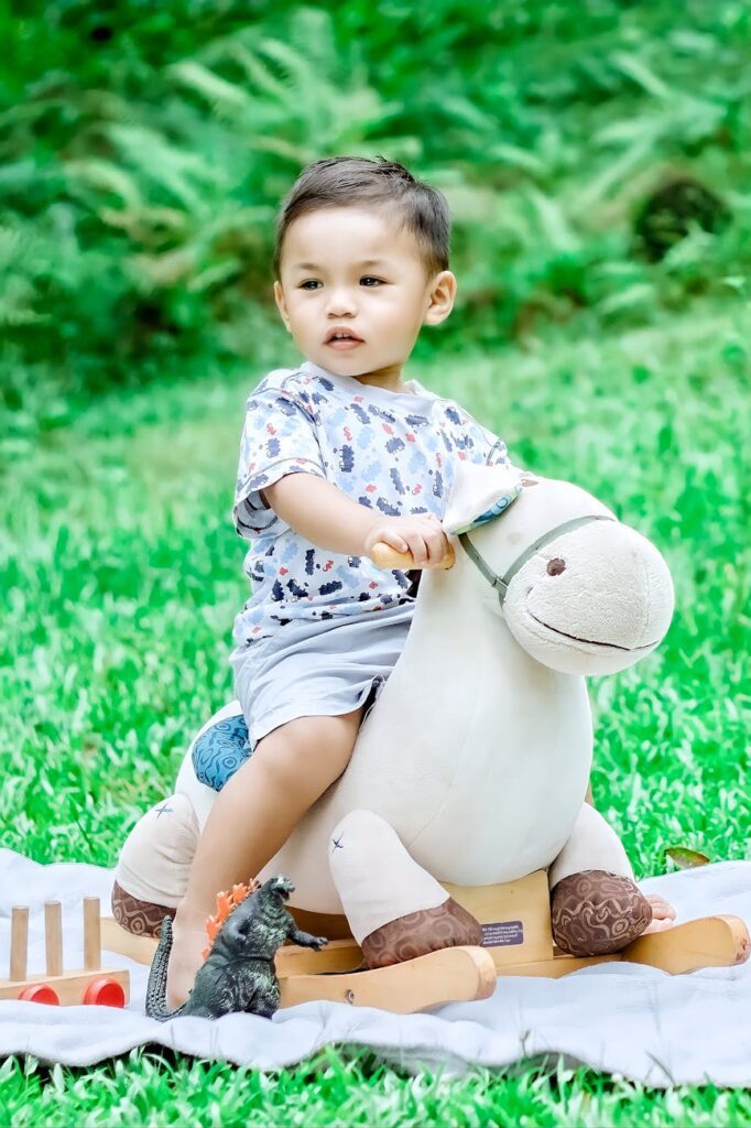 selective focus photo of a cute kid riding a rocking horse