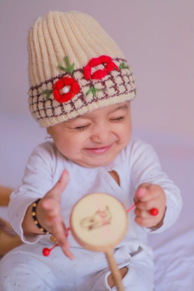 close up shot of a cute baby in a beige knitted cap smiling
